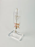 Clear arched acrylic bookmark with Aquarius zodiac lettering, constellation artwork, a pink-and-gold water-bearer symbol, the quote “A mind that finds home in the unusual,” and dangling star and Aquarius heart charms.